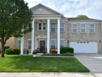Charming two-story home features a columned porch, attached garage, and well-maintained lawn at 10601 Adam Dr, Indianapolis, IN 46231