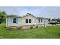 Charming single-story home with light siding, blue shutters, and a well-maintained front lawn and colorful flower bed at 10694 W Hickory Ct, Quincy, IN 47456