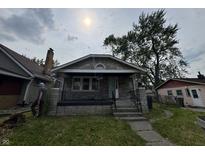 Charming stone home featuring a covered front porch and mature landscaping at 1214 Wallace Ave, Indianapolis, IN 46201