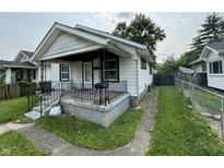 View of a modest white home with a small porch and wrought iron railings, needing some TLC and landscaping at 1226 Hiatt St, Indianapolis, IN 46221