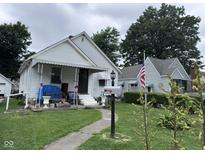 A charming single-story home with a covered porch and an American flag in a mature, tree-lined yard at 1768 N Lynhurst Dr, Speedway, IN 46224