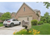 Beautiful brick home with a two-car garage, lush landscaping, and a white SUV parked in the driveway at 1870 Broadleaf Ct # 10, Greenwood, IN 46143