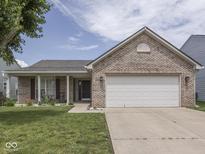 Charming brick home featuring an attached two-car garage, a cozy front porch, and a well-maintained lawn at 2734 Newaygo Dr, Indianapolis, IN 46217