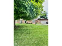 Traditional brick home featuring a well-manicured lawn and mature shade trees at 3130 Taylor Rd, Columbus, IN 47203