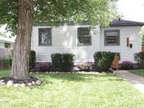 Charming home featuring a landscaped front yard with flowering bushes and a large shade tree at 4445 Kingsley Dr, Indianapolis, IN 46205
