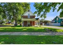 Charming two-story brick home with a covered front porch, green lawn, and mature trees at 590 W Washington St, Martinsville, IN 46151