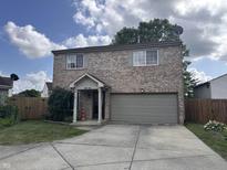 Charming two-story brick home features attached garage, well-kept lawn, and a cozy front porch at 6585 Dunsdin Dr, Plainfield, IN 46168