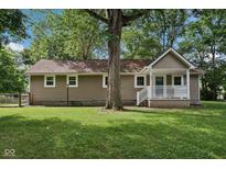 Charming ranch style home featuring neutral siding, a cozy front porch, and a mature tree in the front yard at 7141 E Pleasant Run Pkwy S Dr, Indianapolis, IN 46219