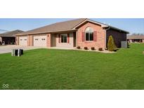 A charming brick house features an attached two-car garage and a well-manicured lawn at 202 Asbury Dr, Anderson, IN 46013