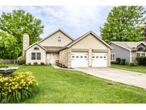 Charming home features a two-car garage, stone accents, and a well-manicured lawn with colorful flowers at 4380 Dunsany Ct, Indianapolis, IN 46254