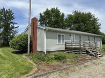 Charming home featuring a red brick chimney and a wooden deck, set amidst a lush green landscape at 4673 S 400 W, New Palestine, IN 46163