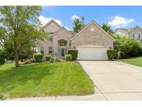 Two-story brick home featuring a well-manicured lawn, mature trees and an attached two car garage at 5857 Stone Pine Trl, Carmel, IN 46033