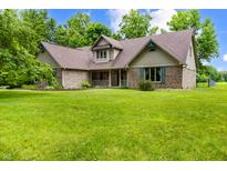 Charming brick home featuring a well-manicured lawn and inviting front porch, set amidst lush greenery at 7533 Deerfield Dr, Greenfield, IN 46140