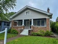 Charming home with a cozy front porch, brick accents, and a well-maintained lawn at 810 N Bosart Ave, Indianapolis, IN 46201
