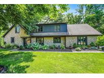 Charming stone-clad home featuring a lush green lawn and meticulously landscaped flower beds at 8924 Stormhaven Ct, Indianapolis, IN 46256