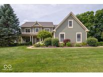 Charming two-story home boasts a lush lawn, mature trees, and inviting curb appeal at 10865 Fairwoods Dr, Fishers, IN 46037