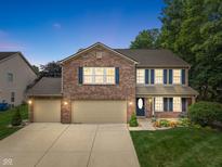 Charming two-story home with brick facade, blue shutters, and well-manicured lawn at dusk at 11763 Igneous Dr, Fishers, IN 46038