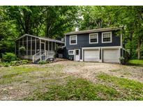 Two-story home with screened-in porch and attached two-car garage surrounded by trees at 1515 Randall Rd, Indianapolis, IN 46240