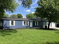 Charming blue home featuring white trim, lush lawn, and mature trees, offering great curb appeal at 221 N 9Th St, Elwood, IN 46036