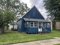 Charming blue home with a well-maintained front yard, inviting curb appeal and a quaint front porch at 3127 E Lynn St, Anderson, IN 46016