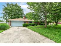 Charming single-story brick home with a blue garage door and a long driveway, surrounded by mature trees and greenery at 3636 Oakwood Dr, Anderson, IN 46011