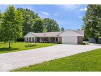 Brick home with white siding and a gravel driveway, surrounded by lush greenery at 881 W 1050 N, Fortville, IN 46040