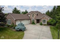 Beautiful brick home featuring an attached three car garage, driveway, and mature trees at 10455 Trewithen Ln, Carmel, IN 46032
