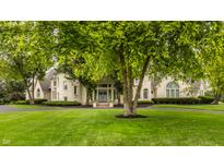 Stunning brick home featuring a lush green lawn, mature trees, and a circular driveway at 1089 Laurelwood, Carmel, IN 46032