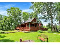 Charming log cabin with a wraparound porch and lush green lawn, perfect for outdoor living at 1155 Cope Rd, Martinsville, IN 46151