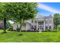 Charming brick home features a well-manicured lawn, mature tree, and inviting front porch with white columns at 3345 Kilkenny Cir, Carmel, IN 46032