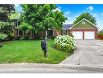 Charming two-story home with a lush green lawn, mature trees, and a well-manicured garden bed at 58 Penn Pl, Zionsville, IN 46077