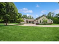 Stunning single-story home featuring a manicured lawn, circular driveway, and elegant architectural design at 6115 Stonegate Run, Zionsville, IN 46077