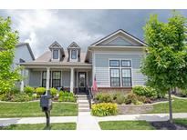 Charming home with inviting front porch, lush landscaping, and an American flag at 1580 Mairn Ave, Carmel, IN 46032
