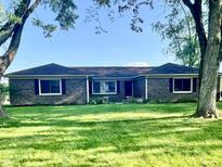 Charming brick home with mature trees and a well-manicured lawn under a bright sky at 15841 E 265 N, Columbus, IN 47203