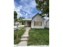 Modest home featuring a front porch, boarded windows and a small, grassy front yard at 1902 Orange St, Indianapolis, IN 46203