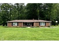 Charming brick ranch home featuring a well-manicured lawn and beautiful, mature trees offering shade and privacy at 1980 S Arthur Rd, Paragon, IN 46166
