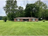 Charming brick ranch home with a well-manicured lawn, mature trees, and classic black shutters at 1980 S Arthur Rd, Paragon, IN 46166