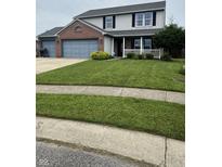 Charming two-story home featuring a well-manicured lawn and a welcoming front porch at 6027 Moonseed Cir, Indianapolis, IN 46203