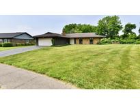 Charming single-story home with a brick and wood exterior, attached garage, and a well-manicured lawn at 6851 Azalea Dr, Indianapolis, IN 46214