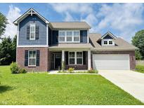 Charming two-story home featuring a brick and blue wood facade, with a well-manicured lawn at 980 S Raylee Garden Dr, New Palestine, IN 46163