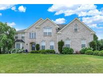 Charming two-story brick home with a lush green lawn, mature trees, and blooming hydrangeas at 10587 Proposal Pointe Way, Fishers, IN 46040