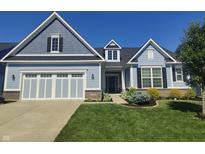 Charming blue home featuring a two-car garage, dormer window, and professionally landscaped front yard at 12634 Mustard Seed Ct, Fishers, IN 46038