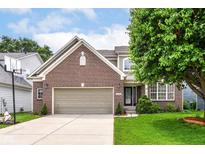 Charming brick front home featuring an attached two-car garage and a well-manicured lawn at 13700 Stanford Dr, Carmel, IN 46074