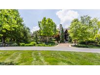 Stunning stone and wood home with lush landscaping, mature trees, and a circular driveway creates great curb appeal at 18 Lost Run Ln, Zionsville, IN 46077