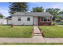 Charming single-story home with a well-manicured lawn and American flags lining the sidewalk leading to the front door at 206 Allen Ln, Greenfield, IN 46140