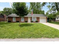 Charming brick home with attached garage, manicured lawn, and American flag at 220 E Tilden Dr, Brownsburg, IN 46112