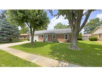 Charming brick ranch home featuring mature trees and a well-maintained lawn at 408 Ottawa Dr, Indianapolis, IN 46217