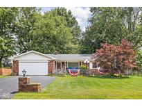 Charming single-story brick home featuring an attached garage and a well-maintained front yard and patriotic decor at 7651 Sherry Ln, Brownsburg, IN 46112