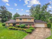 Beautiful tan home with a two-car garage, mature trees, and a well manicured front yard at 904 Dreamy St, Greenwood, IN 46142