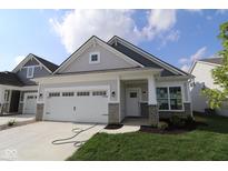 Charming home featuring a two-car garage, stone accents, and a well-manicured lawn on a sunny day at 10604 Maidenhair Dr, Indianapolis, IN 46239